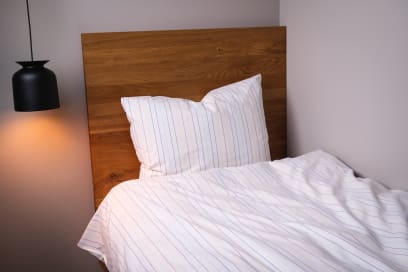 Kissenbezug mit dünnen, bunten Streifen sowie Hotelverschluss und Bogenabnähern.
